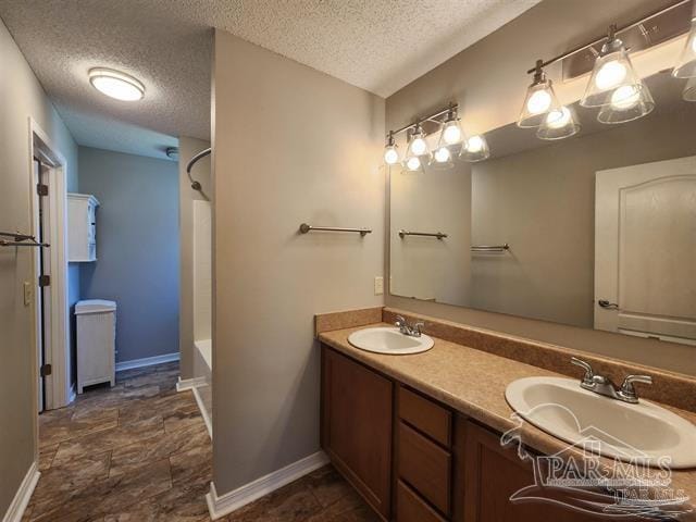 bathroom with vanity, washtub / shower combination, and a textured ceiling