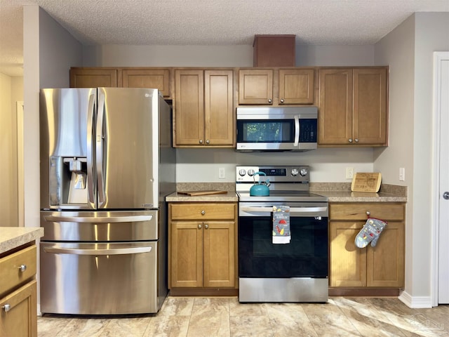 8037 Nalo Creek Loop, Pensacola, FL 32514 - kitchen featuring stainless steel appliances, light countertops, a textured ceiling, and brown cabinetry