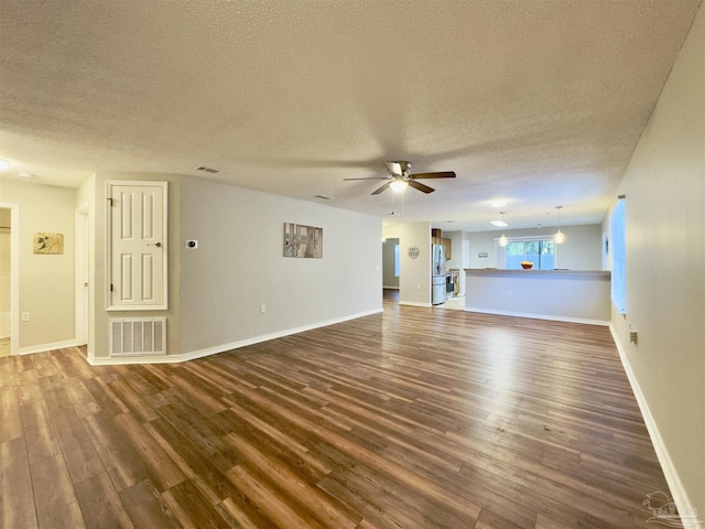 unfurnished living room with ceiling fan, dark hardwood / wood-style flooring, and a textured ceiling