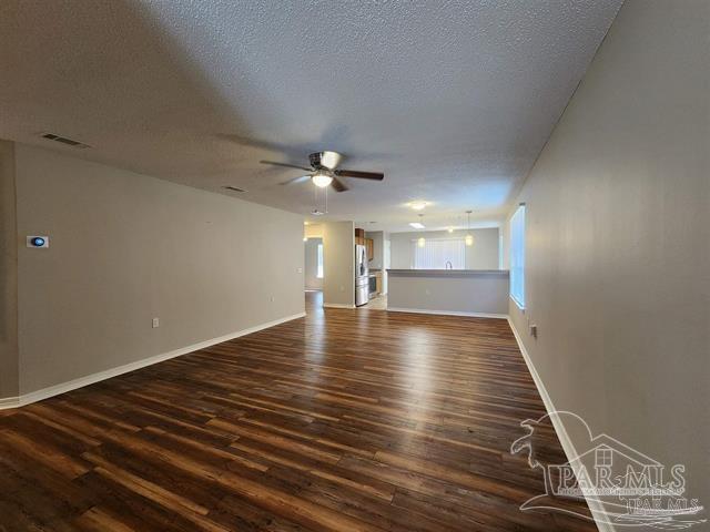 unfurnished living room featuring ceiling fan, dark hardwood / wood-style flooring, and a textured ceiling