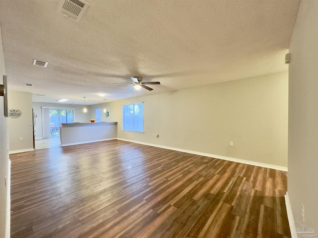 unfurnished living room featuring ceiling fan, dark hardwood / wood-style flooring, and a textured ceiling