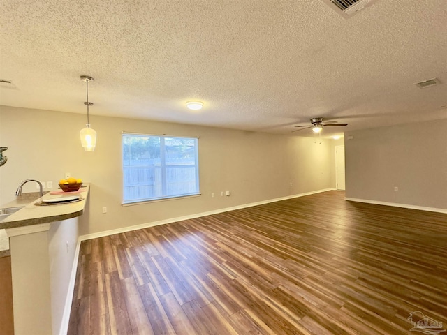 unfurnished living room with a textured ceiling, ceiling fan, dark wood-type flooring, and sink