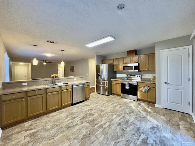 kitchen featuring a textured ceiling, stainless steel appliances, ceiling fan, sink, and decorative light fixtures