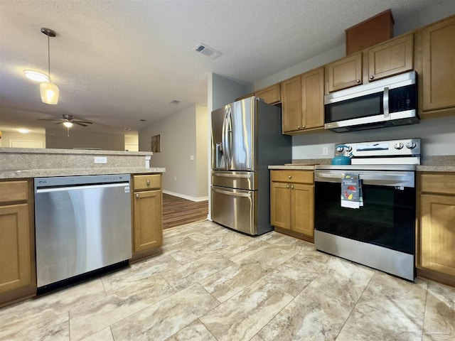 kitchen with pendant lighting, a textured ceiling, stainless steel appliances, and ceiling fan