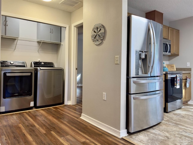 interior space featuring a textured ceiling, light hardwood / wood-style flooring, and washing machine and clothes dryer