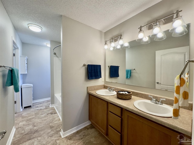 bathroom with washtub / shower combination, vanity, and a textured ceiling