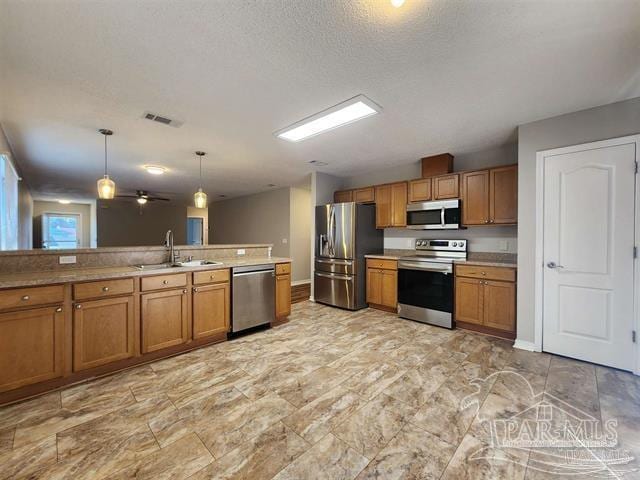 kitchen with sink, ceiling fan, a textured ceiling, decorative light fixtures, and stainless steel appliances