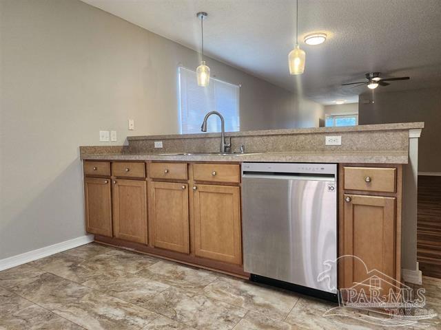 kitchen with stainless steel dishwasher, hanging light fixtures, a healthy amount of sunlight, and sink