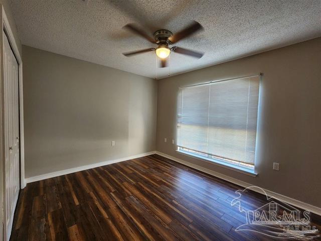 empty room with dark hardwood / wood-style floors, ceiling fan, and a textured ceiling