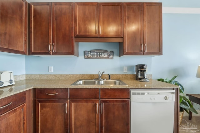 kitchen featuring light stone countertops, sink, and white dishwasher