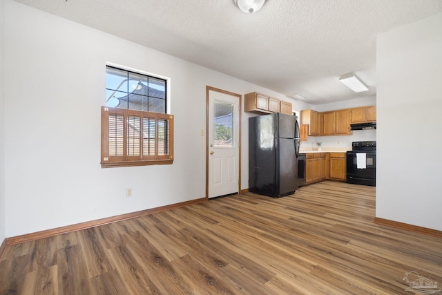 kitchen featuring a textured ceiling, black appliances, and wood-type flooring