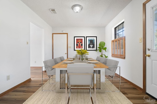 dining area with a textured ceiling and dark wood-type flooring