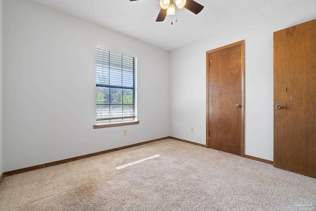 spare room featuring ceiling fan, a textured ceiling, and light colored carpet