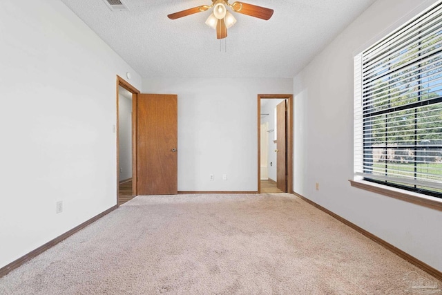 unfurnished bedroom with light carpet, a textured ceiling, and ceiling fan