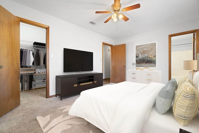 carpeted bedroom featuring ensuite bathroom, a textured ceiling, and ceiling fan