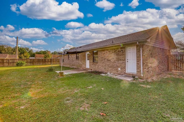 rear view of house featuring a yard and a patio