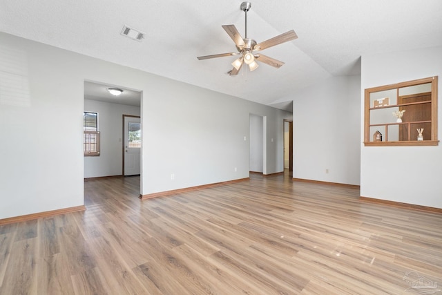 empty room featuring vaulted ceiling, a textured ceiling, light wood-type flooring, and ceiling fan