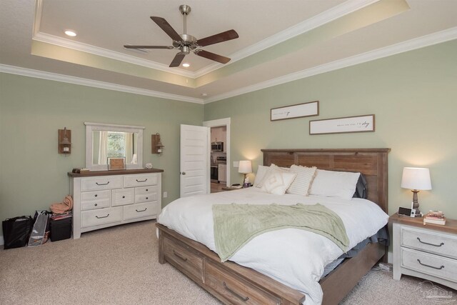 bedroom with ceiling fan, light colored carpet, ornamental molding, and a tray ceiling