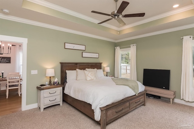 carpeted bedroom with ceiling fan with notable chandelier, a raised ceiling, and ornamental molding