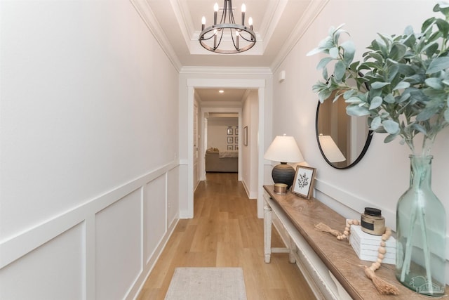 hall with ornamental molding, light hardwood / wood-style floors, and a notable chandelier