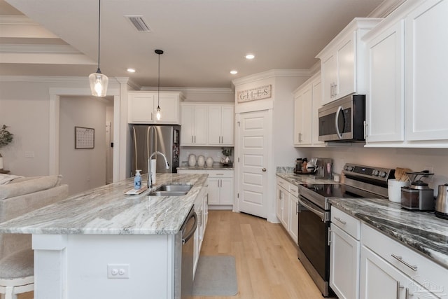 kitchen featuring white cabinets, light hardwood / wood-style floors, decorative light fixtures, and appliances with stainless steel finishes