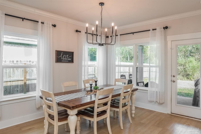 dining room featuring ornamental molding, light hardwood / wood-style flooring, a wealth of natural light, and an inviting chandelier