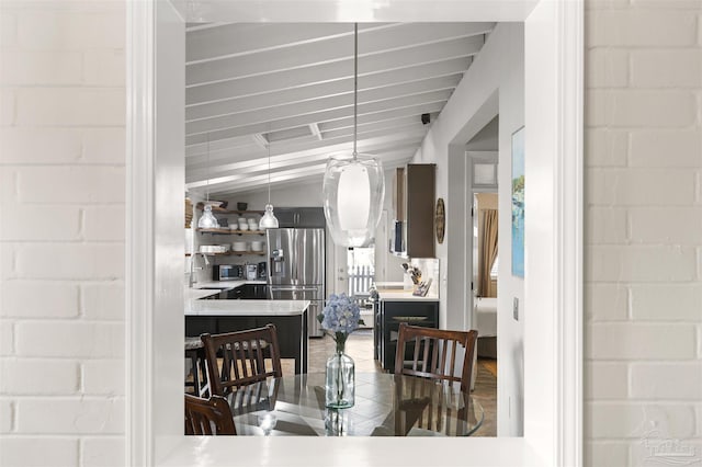 dining space with vaulted ceiling with beams and sink