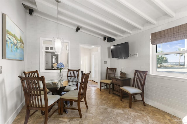 dining room featuring vaulted ceiling with beams and brick wall