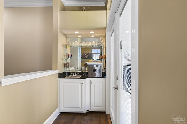 bar featuring dark hardwood / wood-style floors, crown molding, white cabinetry, and sink