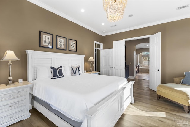 bedroom featuring light wood-type flooring, crown molding, and an inviting chandelier