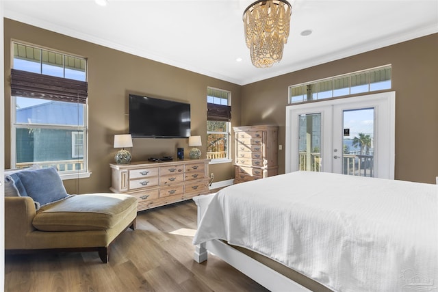 bedroom featuring french doors, crown molding, a chandelier, wood-type flooring, and access to outside