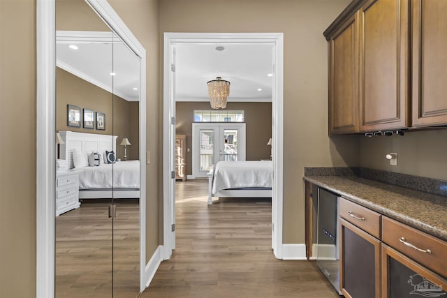 kitchen featuring french doors, dark hardwood / wood-style flooring, dark stone counters, and crown molding