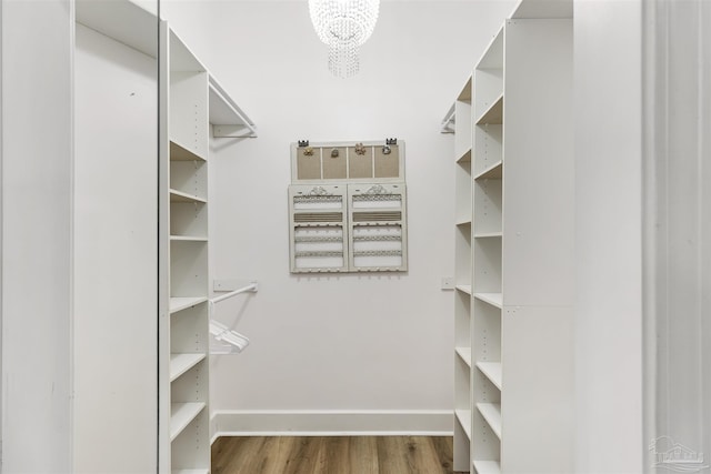 spacious closet featuring dark wood-type flooring and a notable chandelier