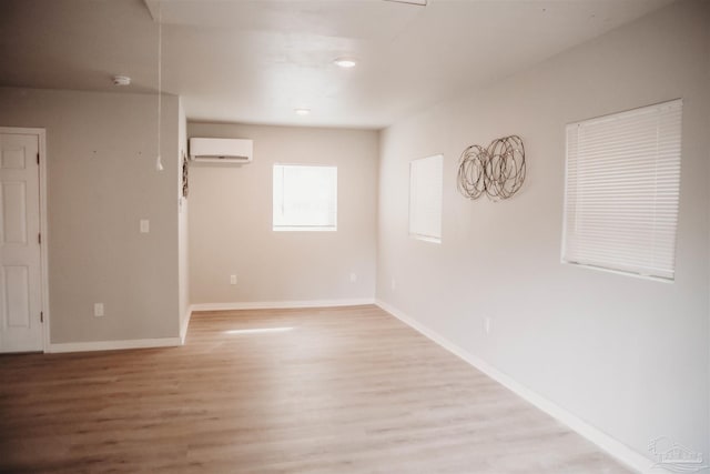 empty room featuring light wood-type flooring and a wall mounted air conditioner