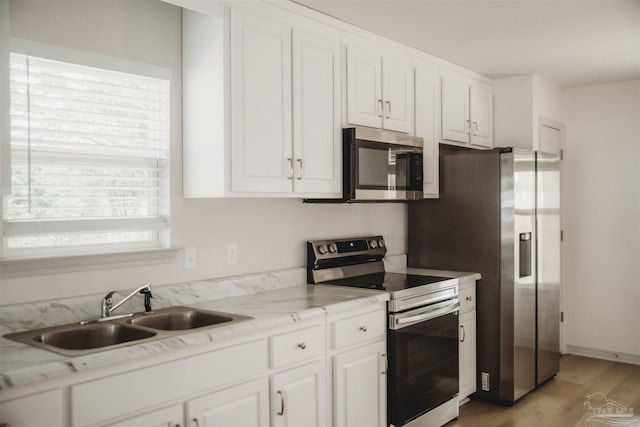 kitchen featuring light stone counters, white cabinets, appliances with stainless steel finishes, and sink