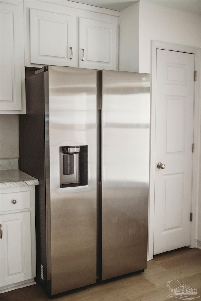 kitchen featuring stainless steel fridge with ice dispenser, light hardwood / wood-style flooring, and white cabinetry