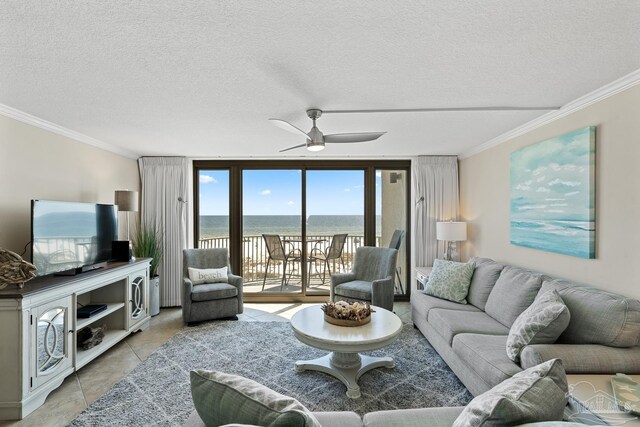 living room with ornamental molding, a water view, light tile patterned floors, and a textured ceiling