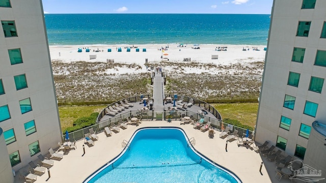 view of swimming pool featuring a view of the beach, a patio area, and a water view