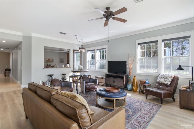 living area featuring visible vents, light wood-style floors, ornamental molding, plenty of natural light, and baseboards