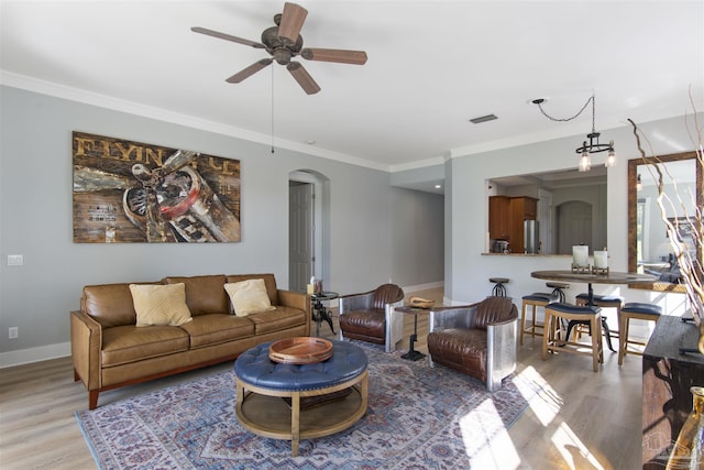 living room with arched walkways, light wood-type flooring, and crown molding