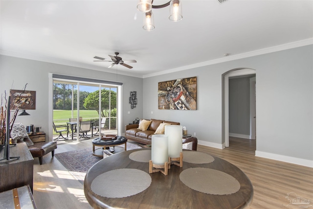 living room with baseboards, arched walkways, crown molding, and wood finished floors