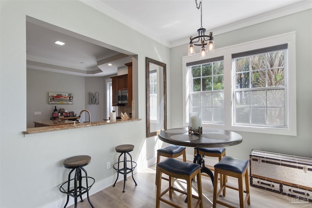 dining area with ornamental molding, a notable chandelier, light wood-style floors, and baseboards