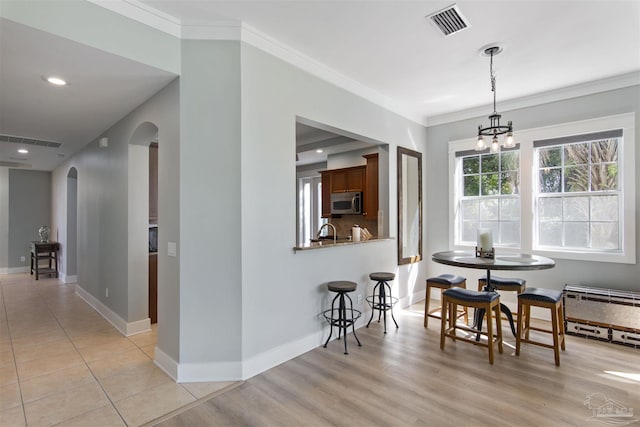 dining area featuring baseboards, visible vents, arched walkways, and ornamental molding