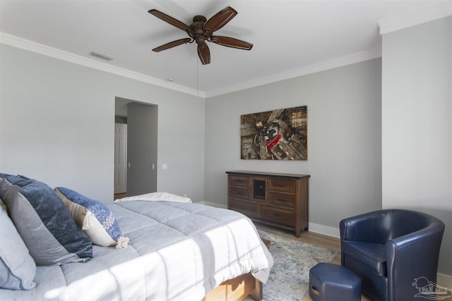 bedroom with ceiling fan, wood finished floors, visible vents, baseboards, and ornamental molding