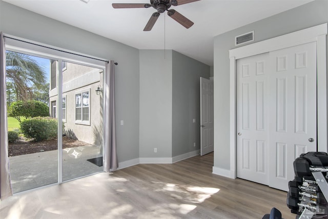 interior space with access to exterior, visible vents, ceiling fan, wood finished floors, and baseboards