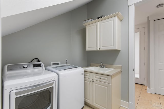 washroom featuring cabinet space, light tile patterned floors, baseboards, separate washer and dryer, and a sink