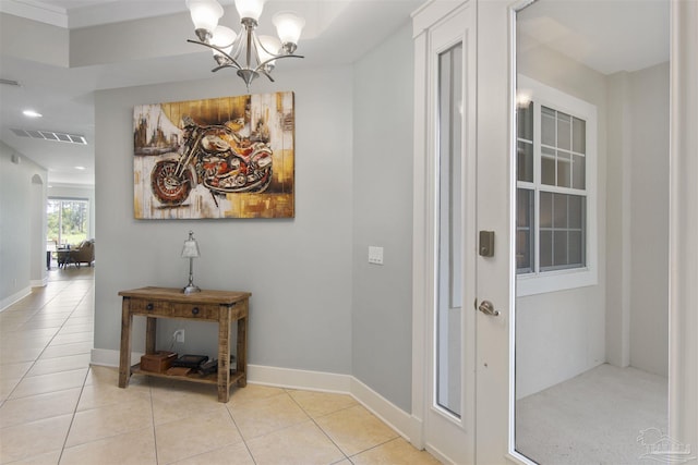 hall with arched walkways, visible vents, an inviting chandelier, tile patterned flooring, and baseboards