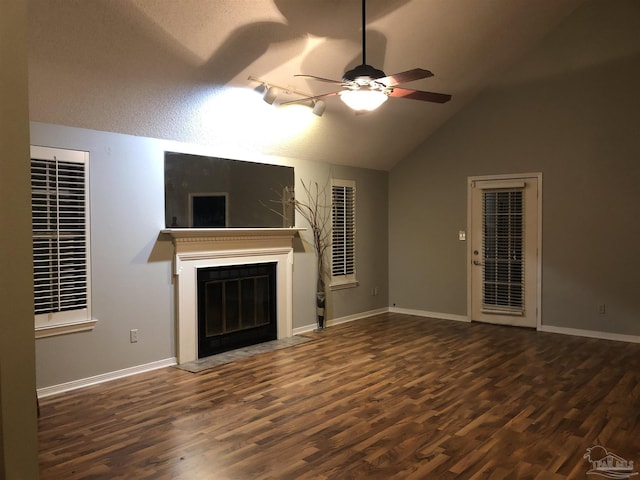 unfurnished living room with a fireplace with flush hearth, vaulted ceiling, ceiling fan, wood finished floors, and baseboards