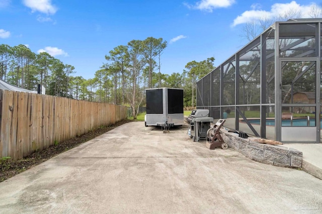 view of patio with an outdoor pool, fence, a grill, and a lanai