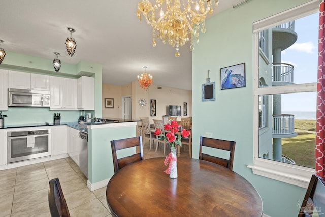 tiled dining space featuring sink, a wealth of natural light, and a chandelier